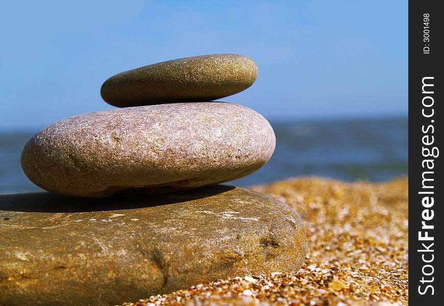 Warm stone on the beach on blue sky background