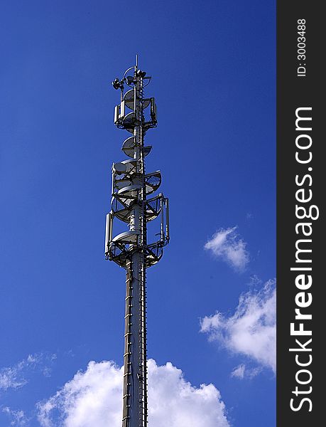 Cell phone antenna pillar in sunny day with white clouds