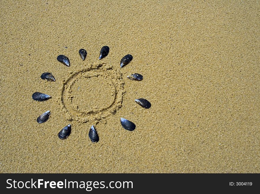 Drawing of the sun in the sand made with shells