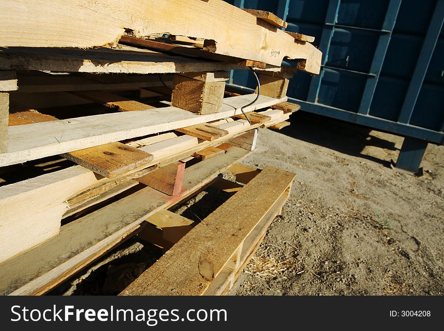 Abstract Stack of Wooden Palettes with Dumpster in the background and dirt ground. Abstract Stack of Wooden Palettes with Dumpster in the background and dirt ground.