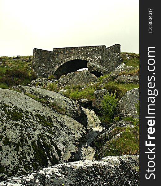 Small stone bridge with small waterfall beneath stands against the mists of the Sally Gap in Wicklow, Ireland. Small stone bridge with small waterfall beneath stands against the mists of the Sally Gap in Wicklow, Ireland