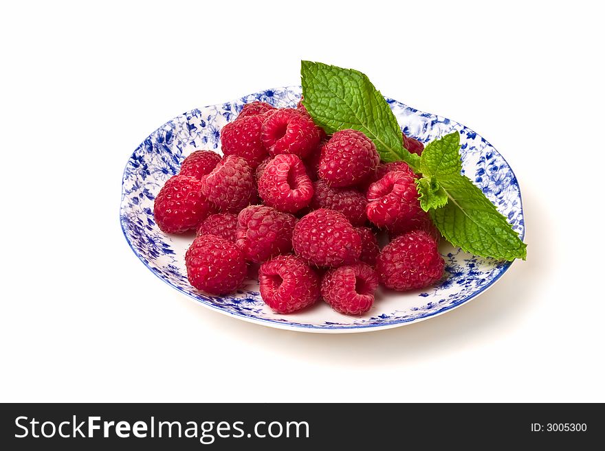 Plate of fresh raspberries decorated with mint leaves