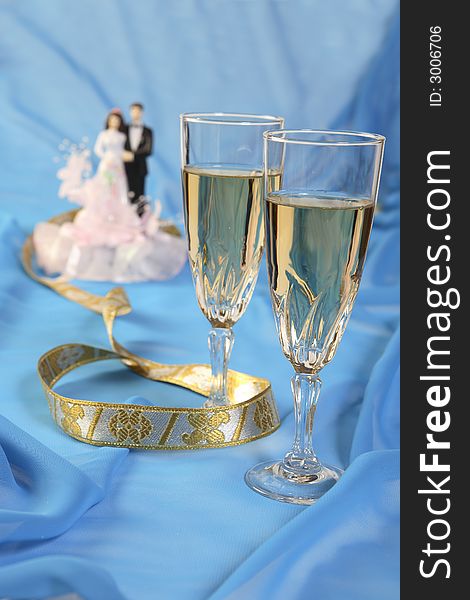 A photo of wedding cake dolls and glasses over blue. A photo of wedding cake dolls and glasses over blue