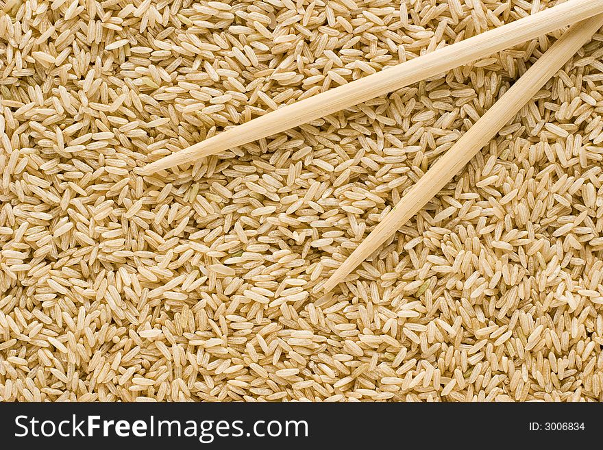 Brown rice background and bamboo chopsticks. Brown rice background and bamboo chopsticks