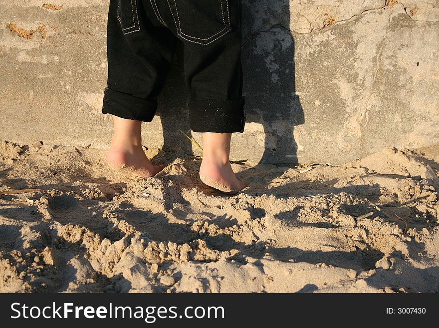 A child's feet on the beach standing halfway on his toes. A child's feet on the beach standing halfway on his toes