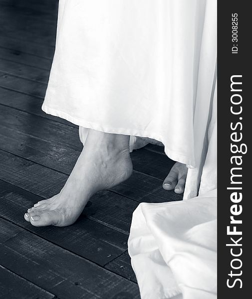 Bride delicately stepping barefooted on wooden floor. Bride delicately stepping barefooted on wooden floor