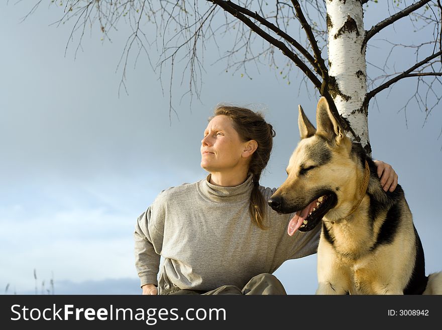 Woman with alsatian dog under birch at sunset. Woman with alsatian dog under birch at sunset