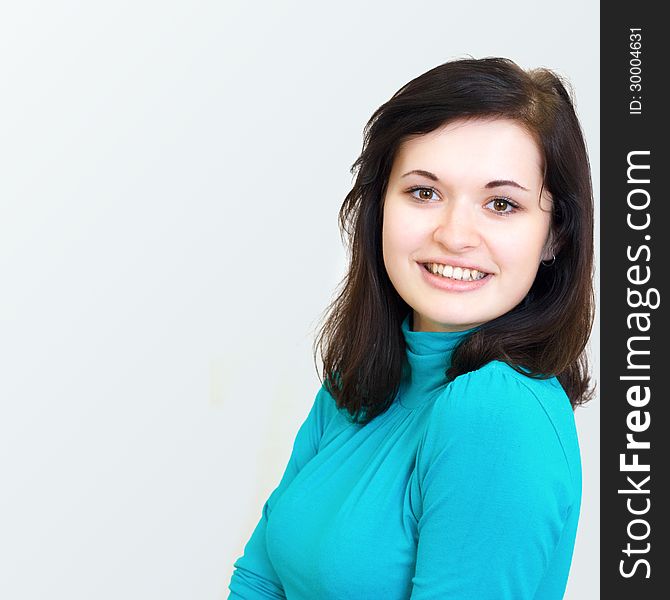 Close-up portrait of a beautiful happy young cheerful brunette smiling girl in the blue sweater. Close-up portrait of a beautiful happy young cheerful brunette smiling girl in the blue sweater