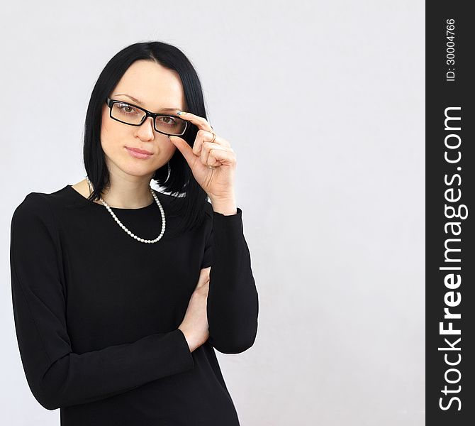 Serious brunette girl in a black dress and sunglasses with a short haircut calm strictly looking at the camera. Serious brunette girl in a black dress and sunglasses with a short haircut calm strictly looking at the camera