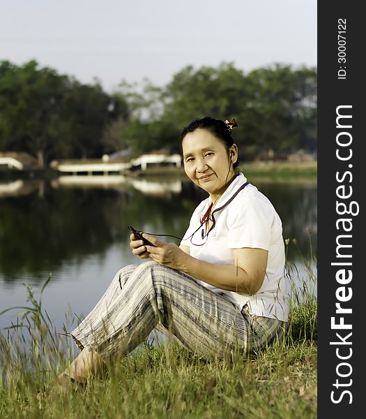 Happy woman on grass listening to music outdoors. Happy woman on grass listening to music outdoors