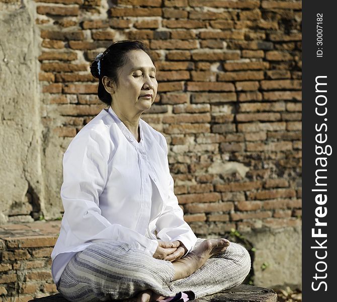 Woman meditating against ancient temple