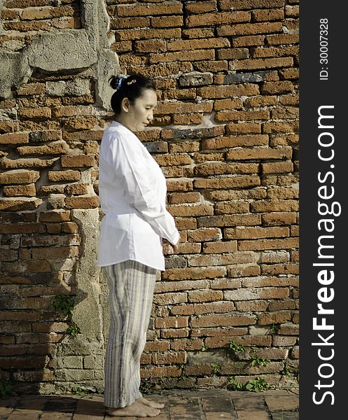 Buddhist woman standing meditating against ancient temple