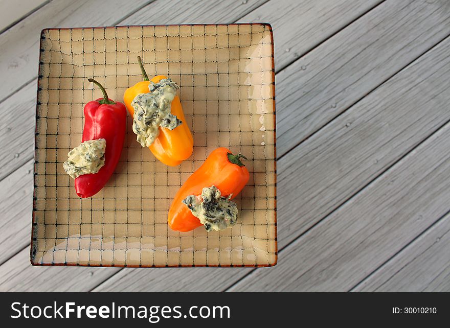 Colorful red,yellow and orange crisp sweet peppers and spinach dip on pretty patterned plate. Colorful red,yellow and orange crisp sweet peppers and spinach dip on pretty patterned plate.