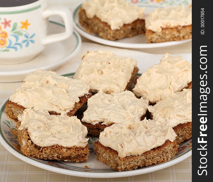 Peanut butter bars on a plate and cup of coffee in background