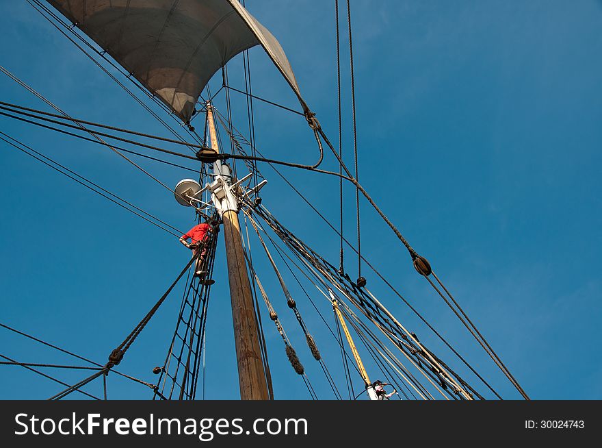 A sailor climbs the rigging of a vintage sailing vessel in Sydney Harbor, Australia. A sailor climbs the rigging of a vintage sailing vessel in Sydney Harbor, Australia.