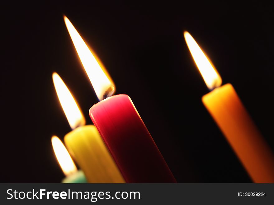 Fascinating candlelight produced by multicolored candles in front of a black background. Fascinating candlelight produced by multicolored candles in front of a black background.