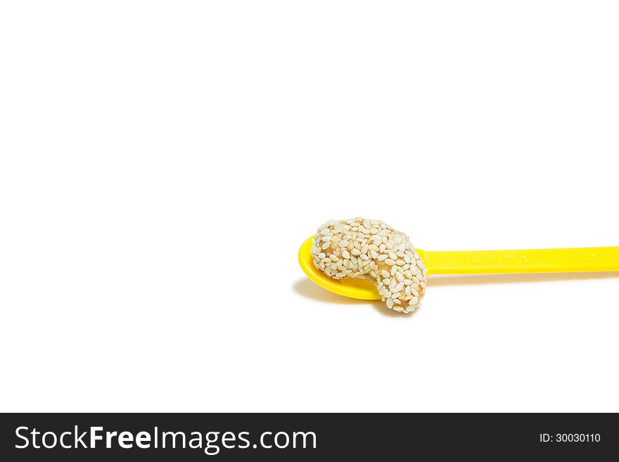 A sweet cashew nut with sesame on yellow spoon