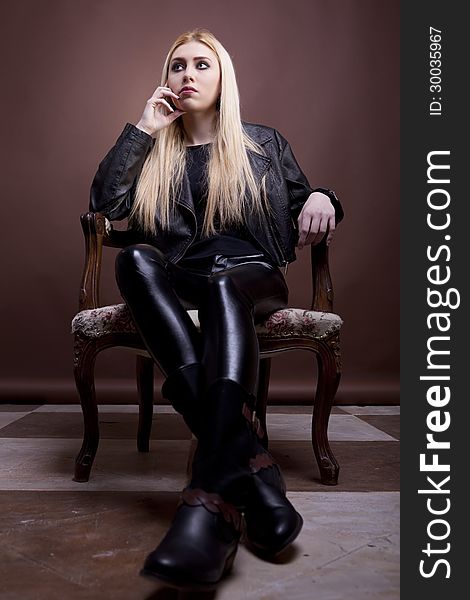 Rocker girl on a vintage chair on brown background studio shot