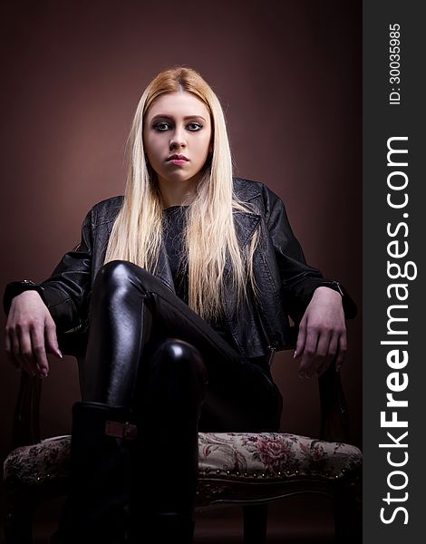 Rock girl sitting on a vintage chair studio shot