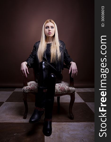 Gorgeous rock girl sitting on a vintage chari full body studio shot