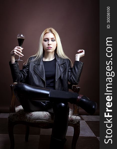 Rock girl holding a glass with dark liquid