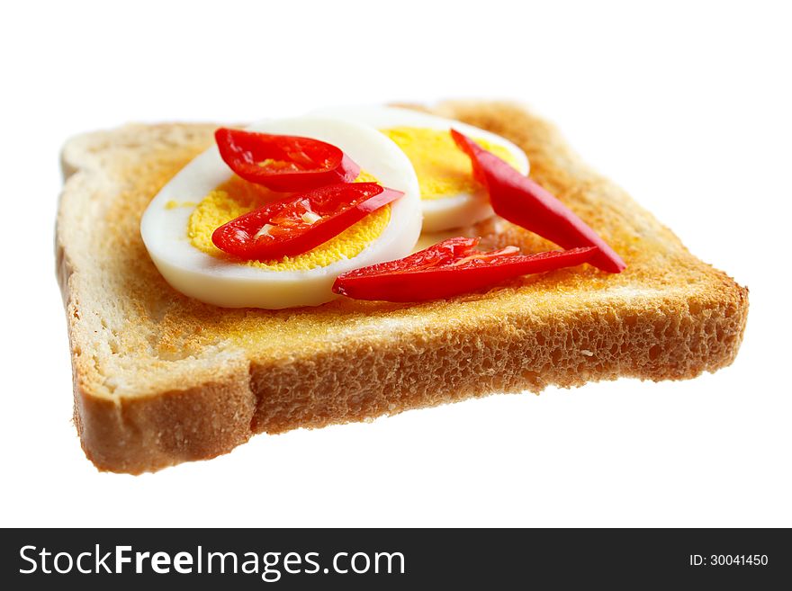 Toasted bread and boiled egg slices with fresh red chili , isolated on white