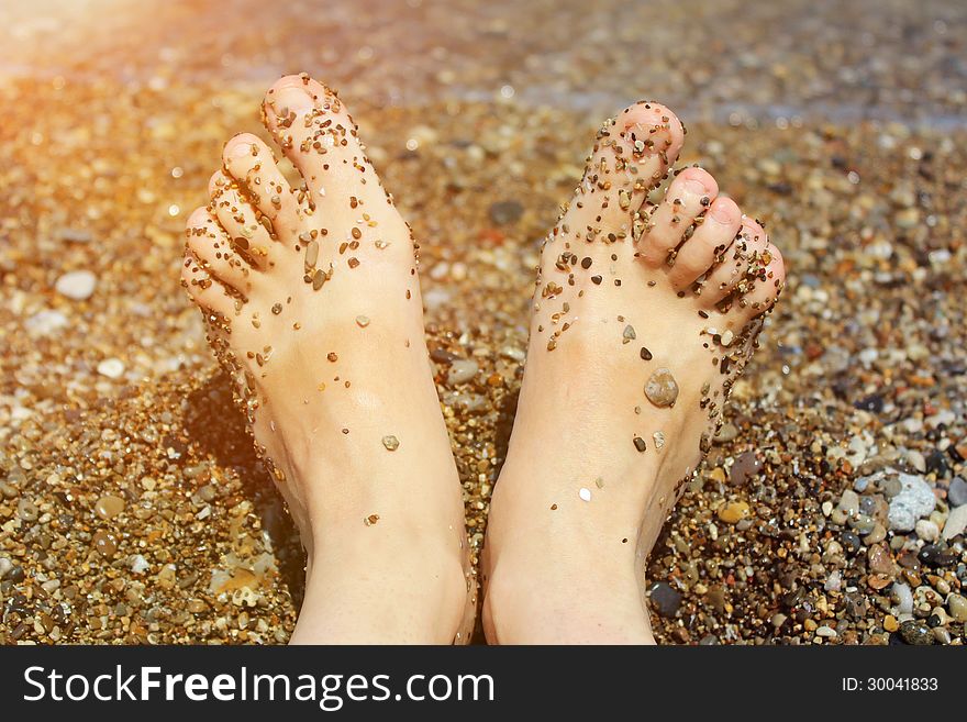Girl`s barefoot legs in the sand