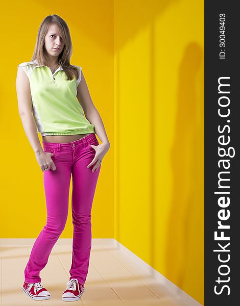 Full length standing lovely blond teenage girl in fashionable outfit, indoor, on bright yellow wall background. Full length standing lovely blond teenage girl in fashionable outfit, indoor, on bright yellow wall background