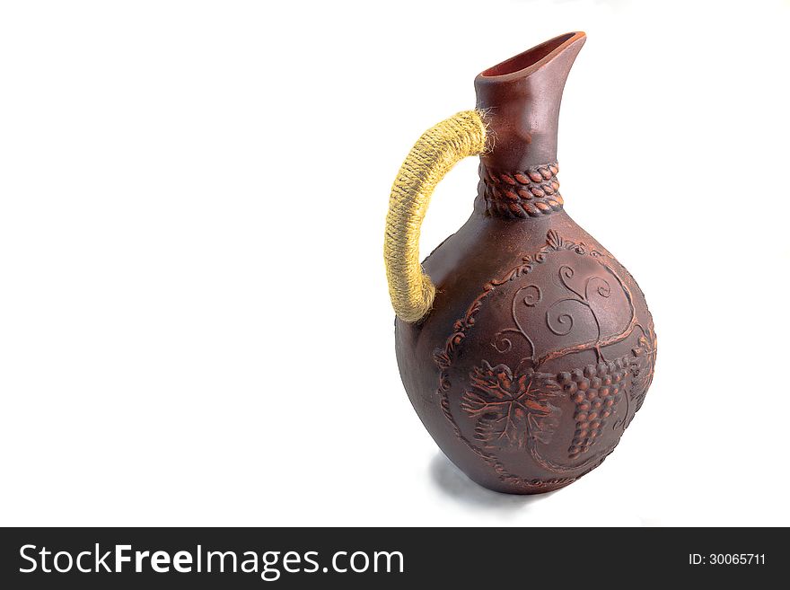 The jug for wine with the handle braided by a lace, is made of red clay, decorated with an ornament, presented on a white background. The jug for wine with the handle braided by a lace, is made of red clay, decorated with an ornament, presented on a white background