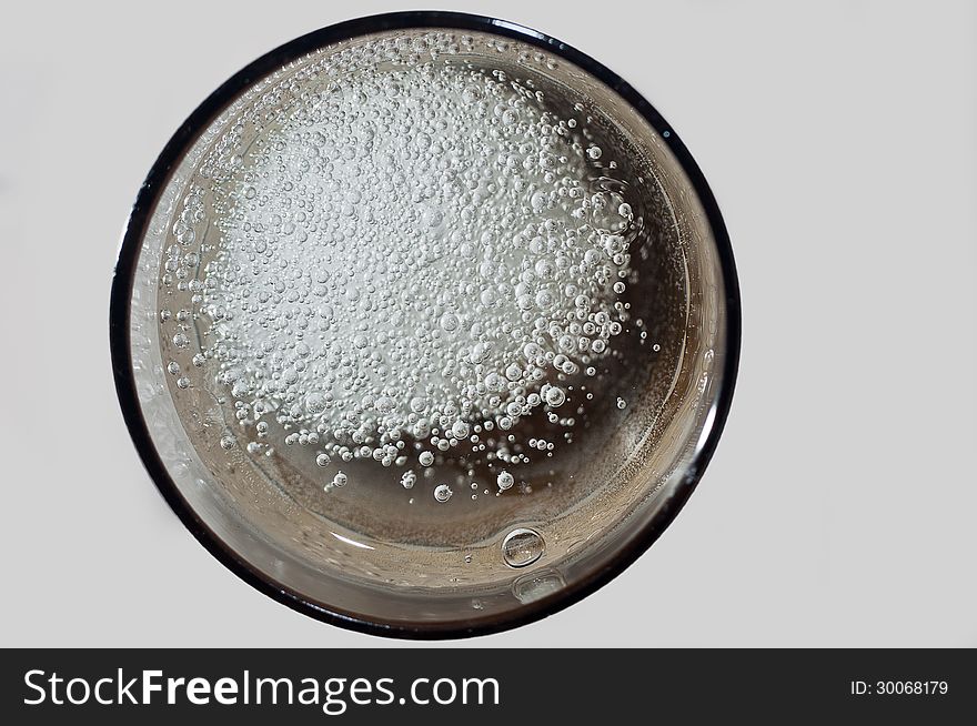 An effervescent pill of magnesium fizzing in a glass of water - seen from above. An effervescent pill of magnesium fizzing in a glass of water - seen from above.