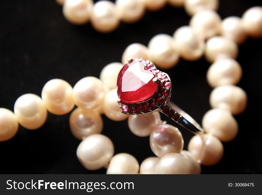 Red heart shaped ruby ring with soft blurred pearl background