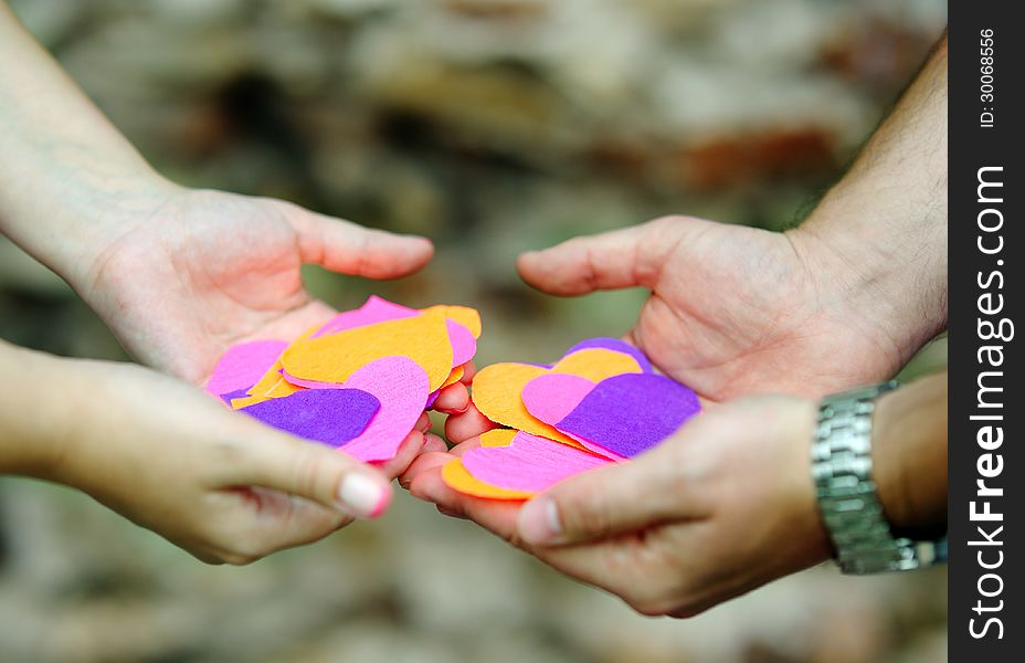 Four hands with beautiful colored paper hearts. Four hands with beautiful colored paper hearts