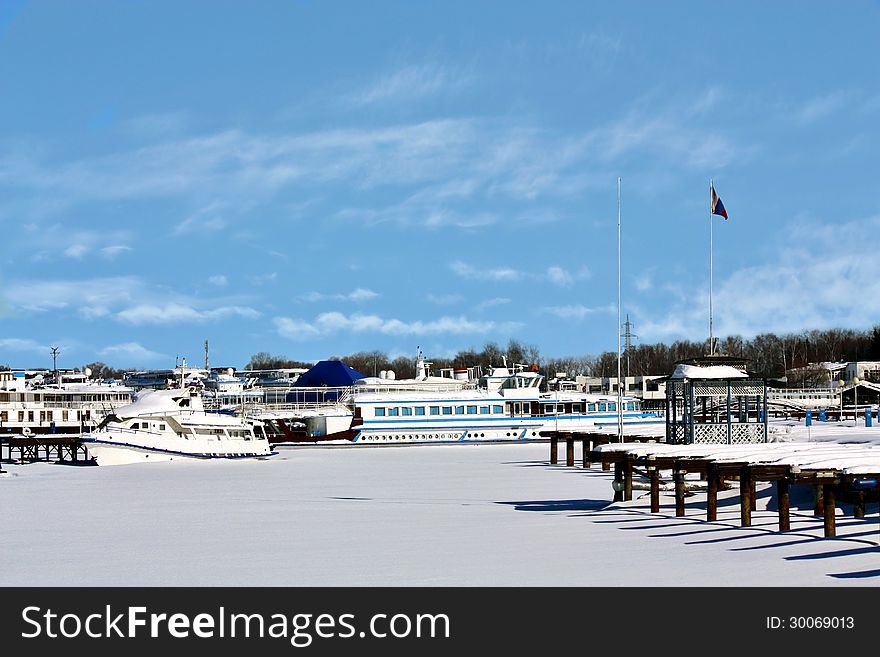 Yachts, boats and river passenger ships in the snow on a winter dock. Yachts, boats and river passenger ships in the snow on a winter dock