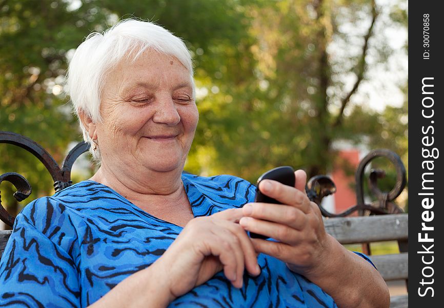 The elderly woman, writes the message in phone. The elderly woman, writes the message in phone