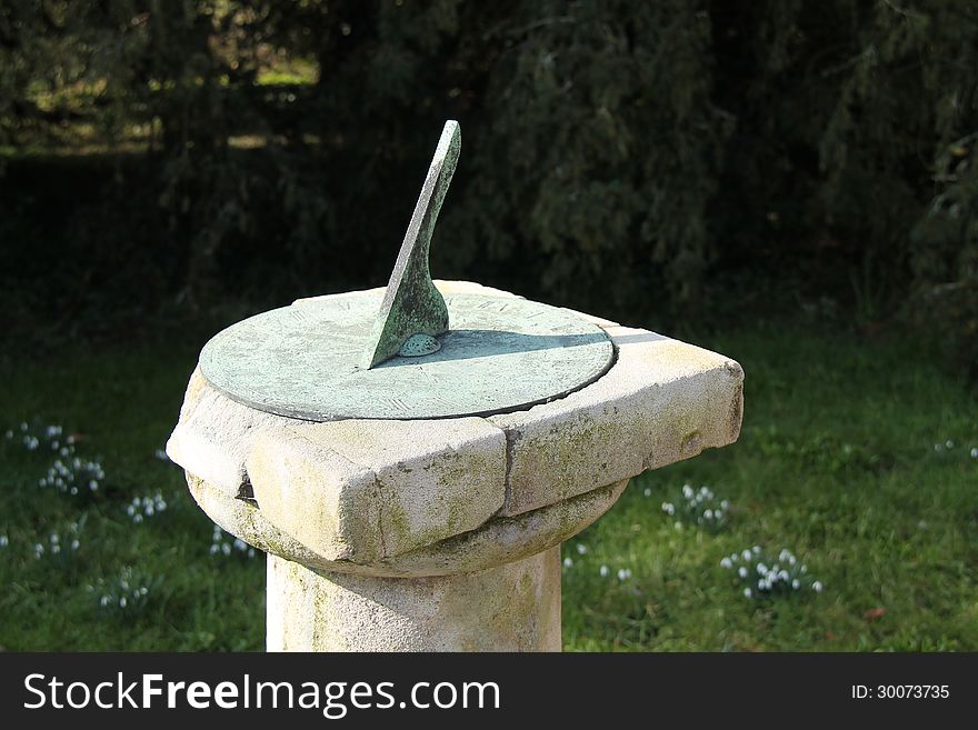 A Traditional Metal Sun Dial Standing on a Stone Plinth. A Traditional Metal Sun Dial Standing on a Stone Plinth.