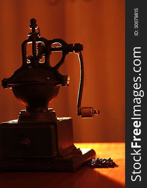 An old coffe grinder with back light and some coffee beans. An old coffe grinder with back light and some coffee beans.