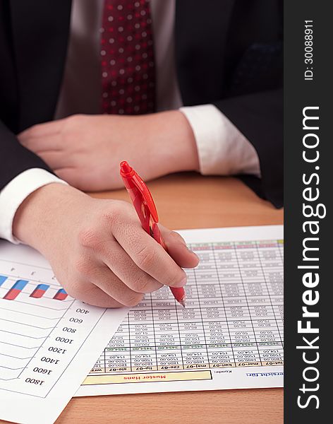 A man in a suit sitting at a desk with financial documents. A man in a suit sitting at a desk with financial documents