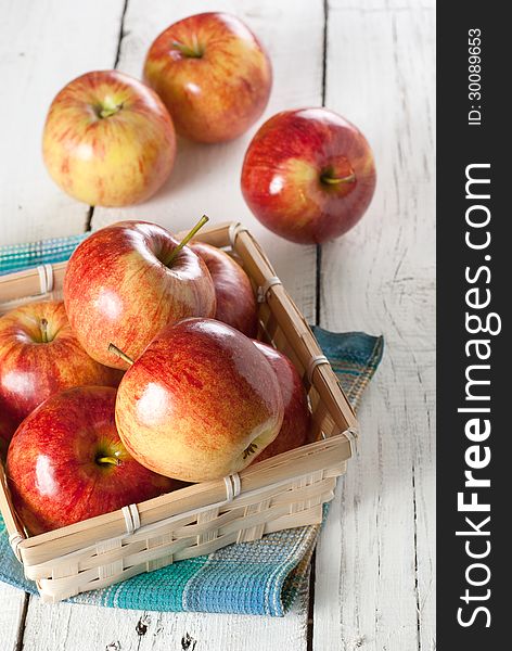 Several of red apples in wicker basket on the white kitchen table