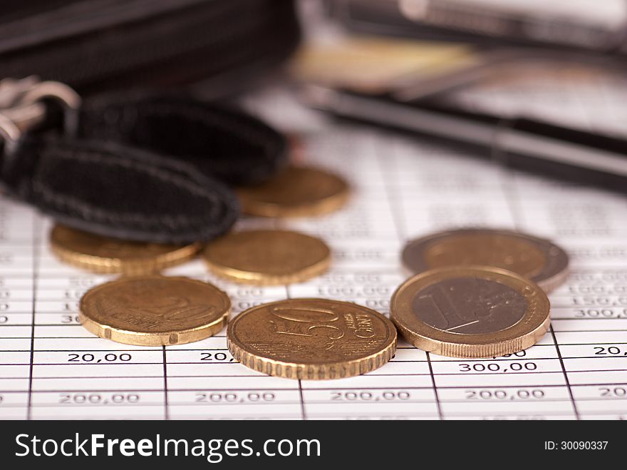 Euro coins arranged on a financial statement with pen and wallet. Euro coins arranged on a financial statement with pen and wallet