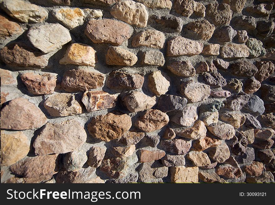 A close up shot of an old wall built from very rough stones. Shot in bright daylight. A close up shot of an old wall built from very rough stones. Shot in bright daylight.