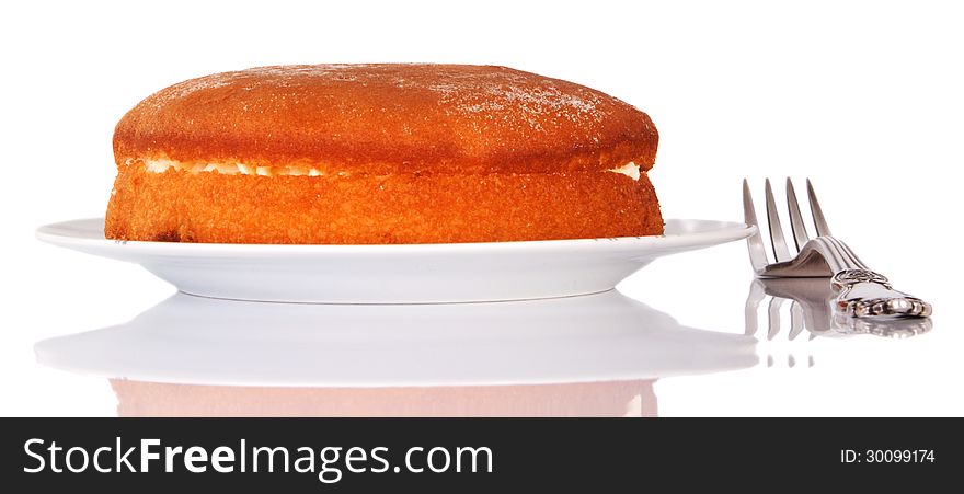 Sponge cake on a plate with a fork on white background with reflection