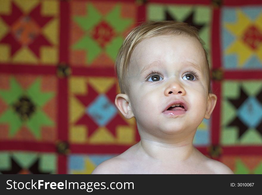 Image of cute toddler with a quilt in the background