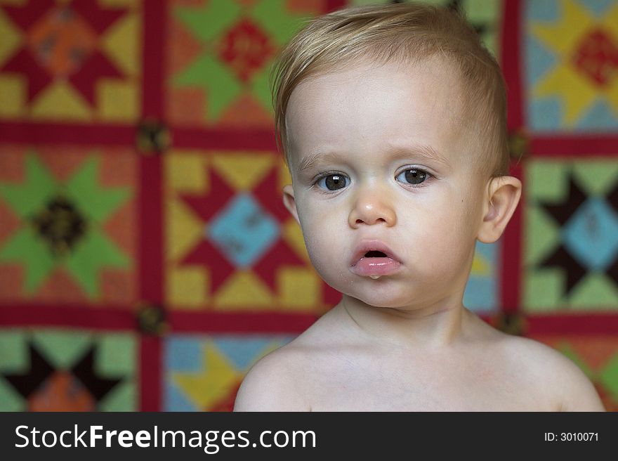 Image of cute toddler with a quilt in the background