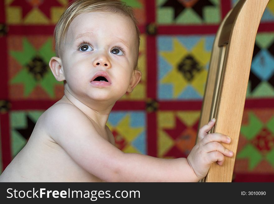 Image of cute toddler with a quilt in the background