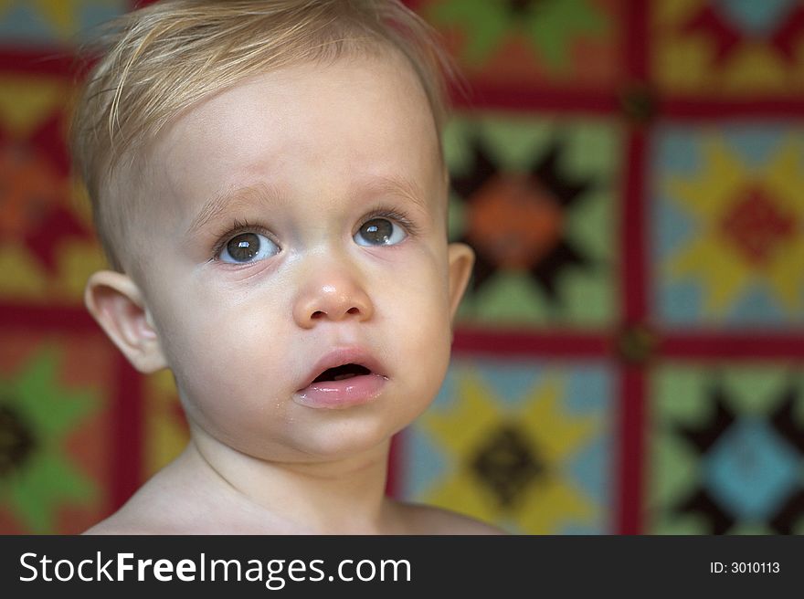 Image of cute toddler with a quilt in the background