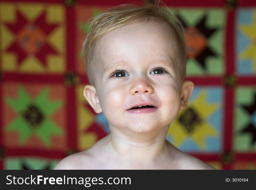 Image of cute toddler with a quilt in the background