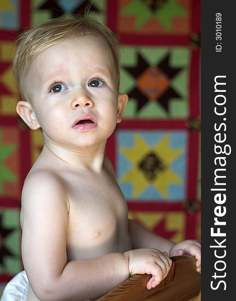 Image of cute toddler with a quilt in the background