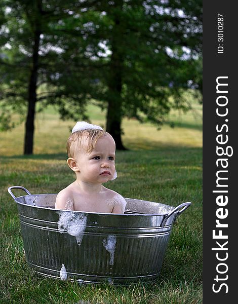 Image of cute toddler sitting in a tub outside. Image of cute toddler sitting in a tub outside