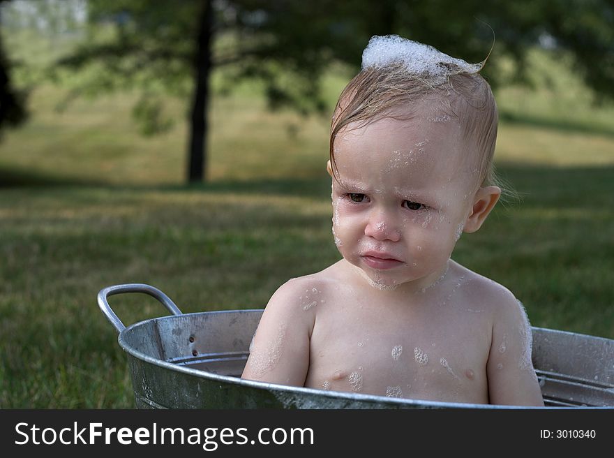 Image of cute toddler sitting in a tub outside. Image of cute toddler sitting in a tub outside