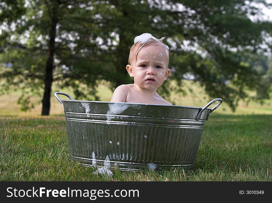 Image of cute toddler sitting in a tub outside. Image of cute toddler sitting in a tub outside